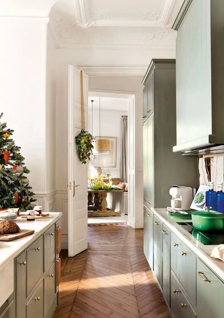 Cocina de frentes verdes con molduras, parquet de espiga y tiradores de latón — estilo clásico renovado