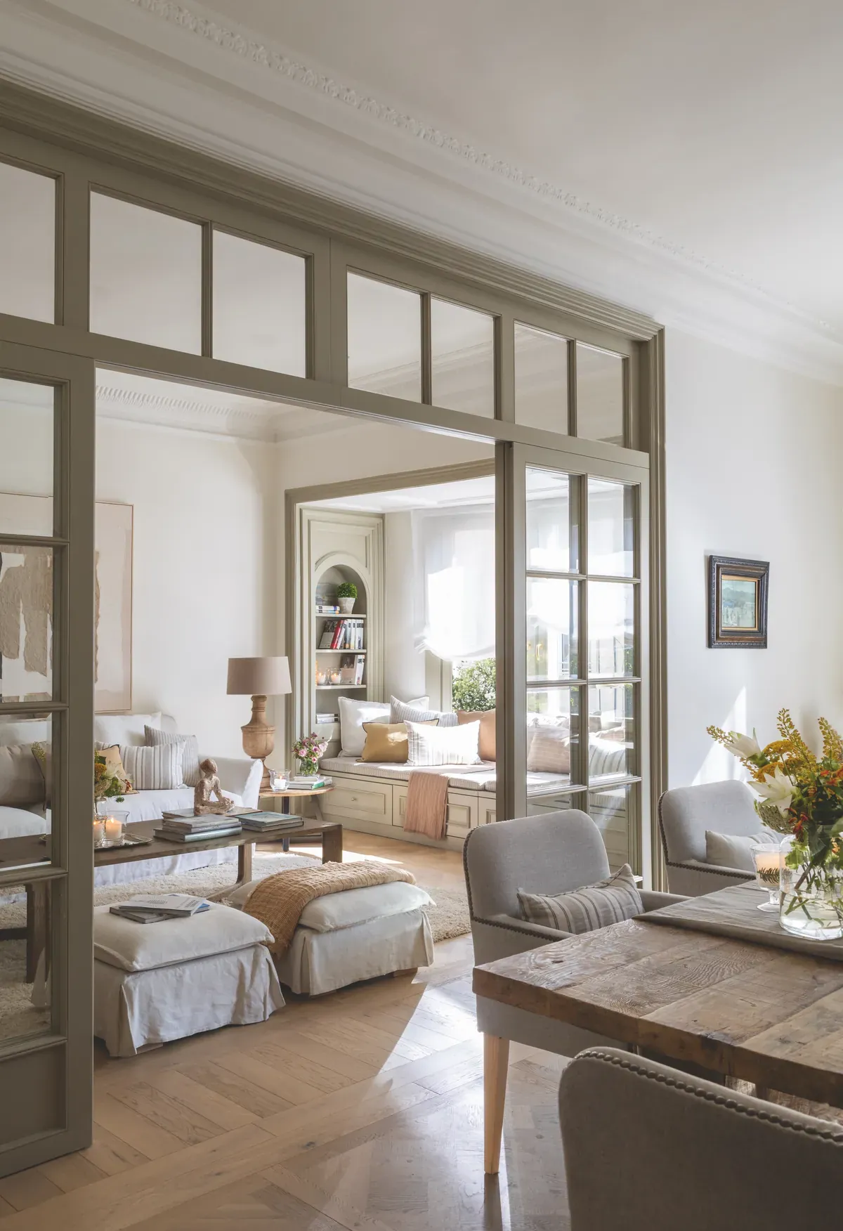 Salón visto desde el comedor a través de cristalera con carpintería clásica y molduras — interiorismo de estilo clásico renovado