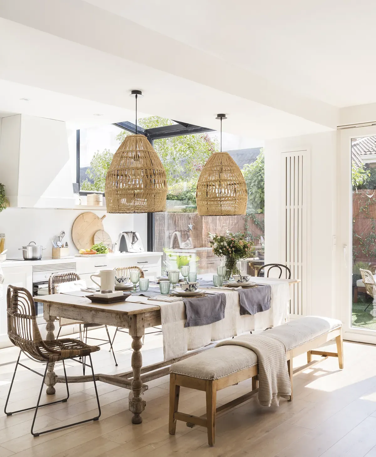 Cocina-comedor abierto y luminoso con lámparas de fibra natural y mesa de madera — interiorismo de estilo mediterráneo